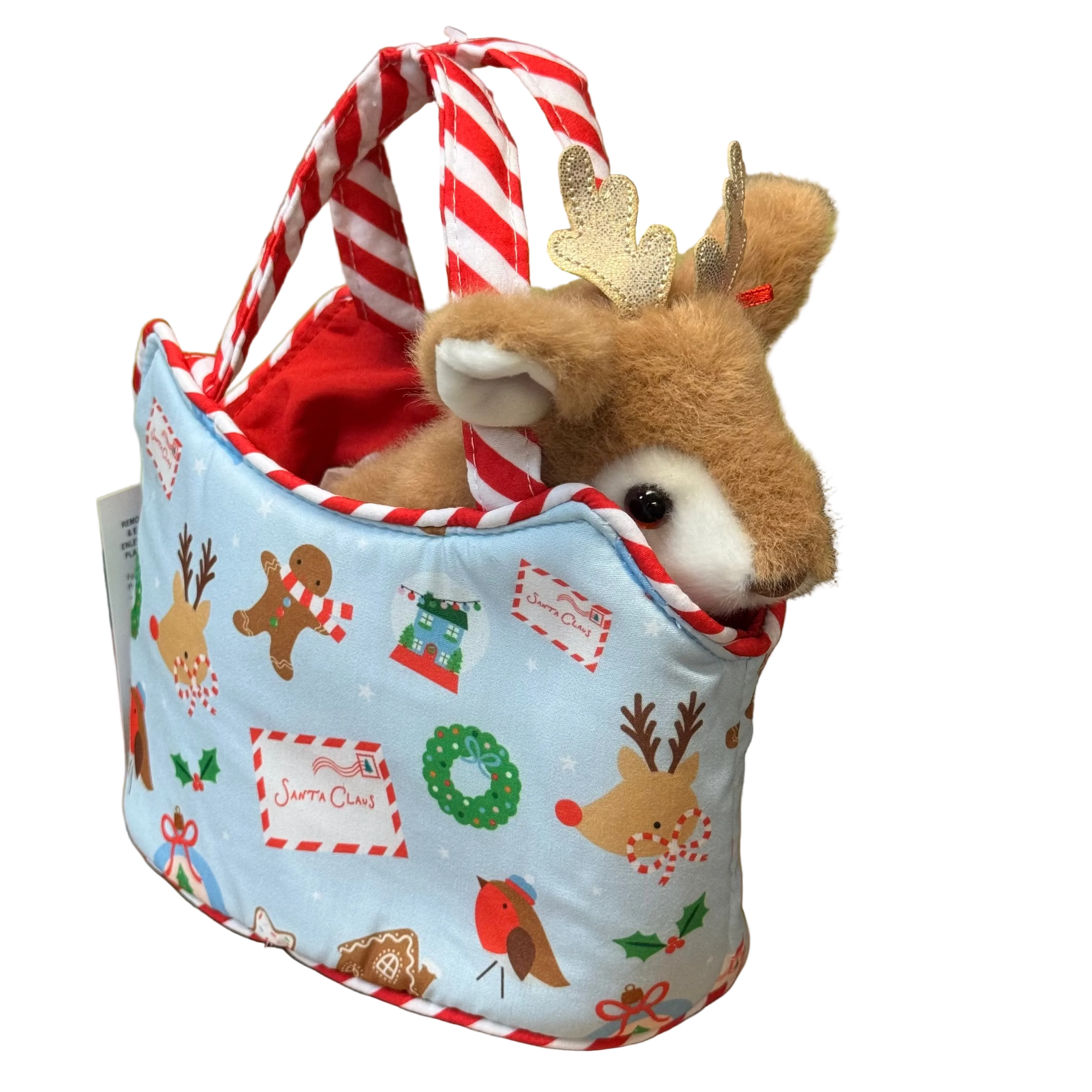 A plush brown deer toy peeking out of a light blue fabric tote bag decorated with red-and-white striped handles and Christmas-themed illustrations, set on a wooden surface.
